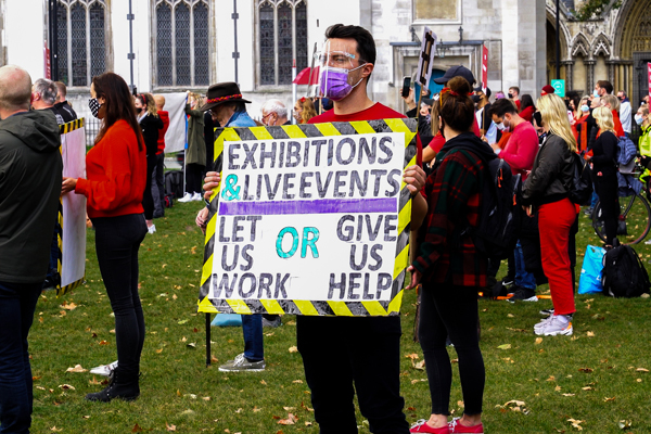 A protestor with a sign that reads: 'exhibitions and live events, let us work or give us help'