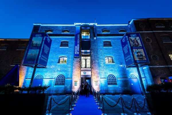 The outside of Museum of London Docklands at night, illuminated by blue light