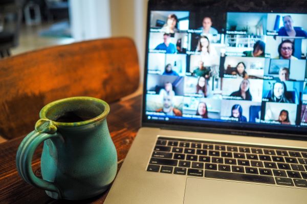 A laptop displaying a zoom call with a blue mug placed next to it