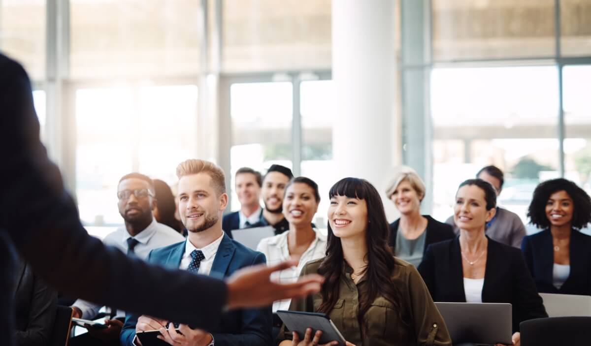 Individual presenting to a happy and engaged audience of corporate professionals