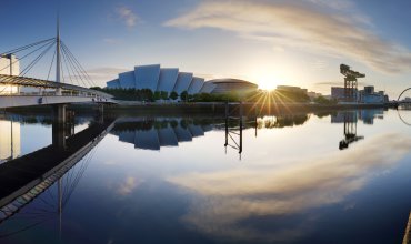 Glasgow Cityscape at sunrise, skyline panorama with reflecion in river with sun, Scotland - UK