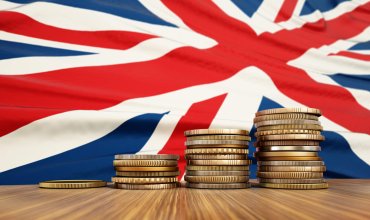 Rising stack of coins with British flag in the background. Economy, finance, interest rates concept