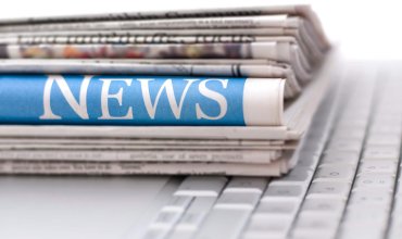 Stack of newspapers resting on laptop keyboard