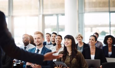Individual presenting to a happy and engaged audience of corporate professionals