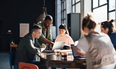 Young professionals or students collaborating in a bright, contemporary co-working environment, displaying teamwork and productivity.